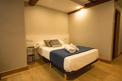 a bedroom with a bed with white sheets and pillows at hostal Nomade Santiago in Santiago de Compostela