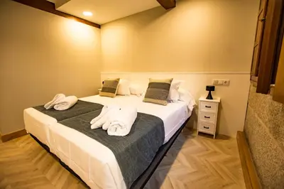 two beds in a room with towels on them at hostal Nomade Santiago in Santiago de Compostela