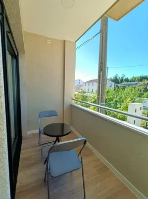 a balcony with two chairs and a table and a window at Pensión Os Mollados in O Pedrouzo