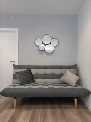 a gray couch in a room with a white wall at Pensión Os Mollados in O Pedrouzo