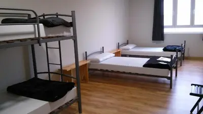 a room with three bunk beds and a wooden floor at Alma del Camino - Rooms & Albergue in Sarria