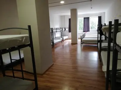 a room with bunk beds and a room with wooden floors at Alma del Camino - Rooms & Albergue in Sarria