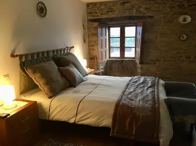 a bedroom with a large bed with a window at Casa da Forxa, renovated former forge/ smithy in Lugo
