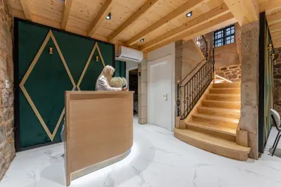 a woman sitting at a counter in a house with a staircase at Hostal HCELENIS in Caldas de Reis