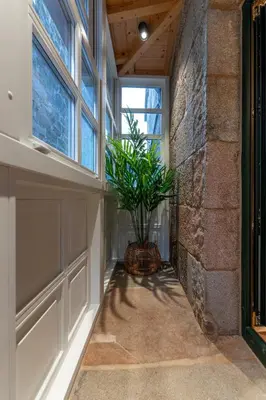 a hallway with a plant in a basket next to a window at Hostal HCELENIS in Caldas de Reis