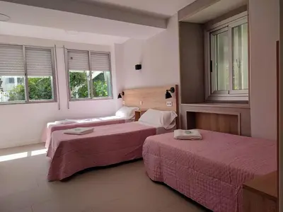 a hotel room with two beds and two windows at Pension-Albergue Don Alvaro in Sarria