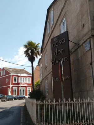 a sign on the side of a building with a palm tree at Pension-Albergue Don Alvaro in Sarria