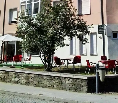 a table and chairs and a tree in front of a building at Pensión-Albergue Puente Ribeira in Sarria