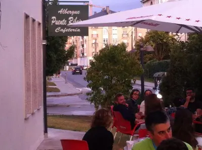 a group of people sitting at a table under an umbrella at Pensión-Albergue Puente Ribeira in Sarria