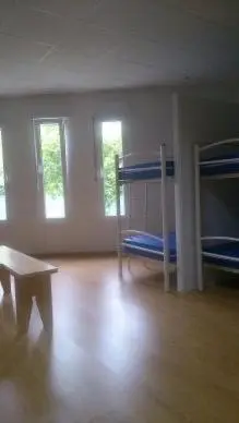 a room with two bunk beds and a wooden floor at Pensión-Albergue Puente Ribeira in Sarria