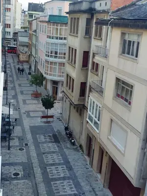 an empty street in a city with buildings at O Lar da Muralla in Lugo