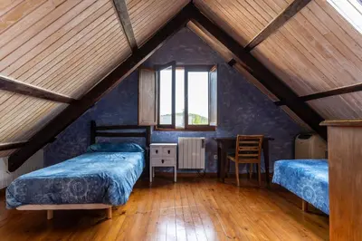a attic bedroom with two beds and a table at Casa de turismo rural Sardom3 in Bembibre