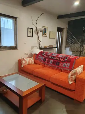 a living room with an orange couch and a coffee table at O pallar in Bardaos