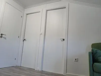 two white closet doors in a room with a chair at O pallar in Bardaos