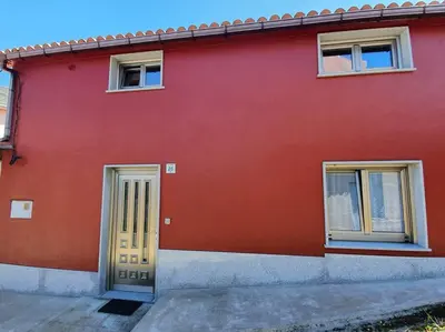 a red house with a yellow door and two windows at O pallar in Bardaos