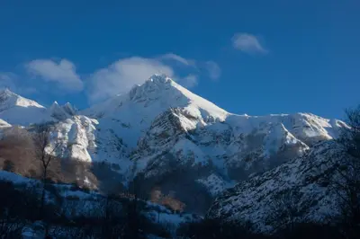 a mountain covered in snow with a blue sky at Apartamentos Rurales Casa Marcelo in Veigas