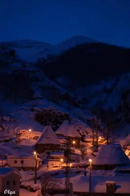 a town covered in snow at night with lights at Apartamentos Rurales Casa Marcelo in Veigas