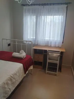 a bedroom with a bed and a desk and a window at La casita del bosque in Lugo