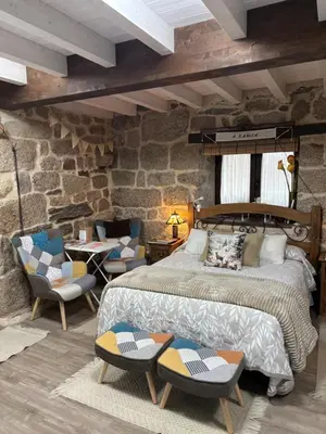 a bedroom with a large bed and two chairs at A Xanela, Casa dos Mestres in Trasmiras