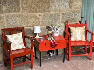 a red table with a doll sitting on it next to two chairs at A Xanela, Casa dos Mestres in Trasmiras