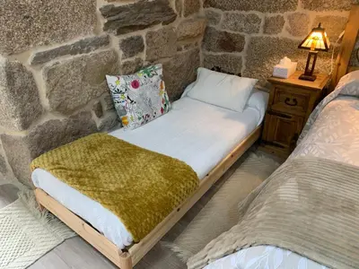 a bed in a room with a stone wall at A Xanela, Casa dos Mestres in Trasmiras