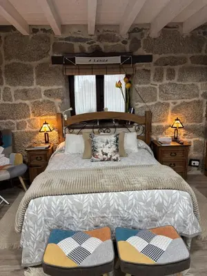 a bedroom with a large bed with two lamps at A Xanela, Casa dos Mestres in Trasmiras