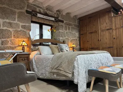 a bedroom with a bed and a stone wall at A Xanela, Casa dos Mestres in Trasmiras