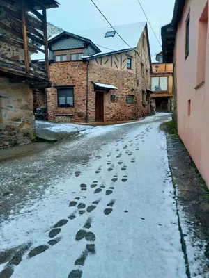 a snow covered alley with footprints in front of a building at Casa de turismo rural Sardom2 in Bembibre