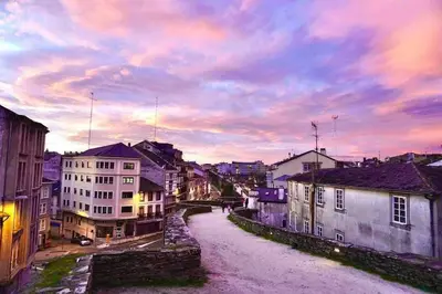 a city street with buildings and a cloudy sky at Apartamento DENTRO DE MURALLA y PARKING GRATUITO en pleno centro in Lugo