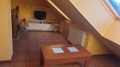 an attic room with a table and a television at Buhardilla Cesar in Lubián