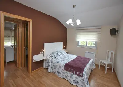 a bedroom with a bed and a bathroom with a sink at Pensión Casa Elena in Reinante