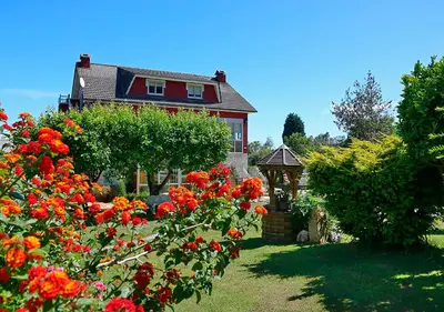 a house with a garden with red flowers and a gazebo at Pensión Casa Elena in Reinante