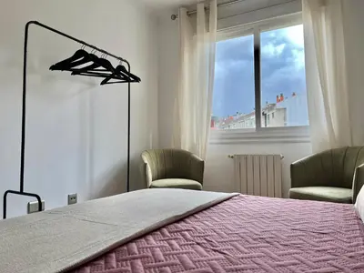 a bedroom with a bed and two chairs and a window at Nuevo Piso en Couto in Ourense
