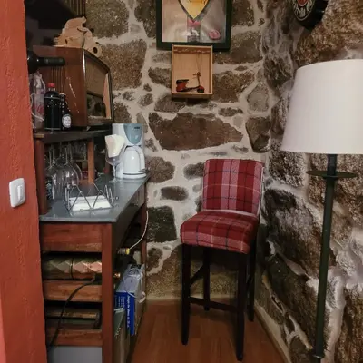 a room with a stone wall with a table and a chair at El Abuelo Angel in Ribadavia