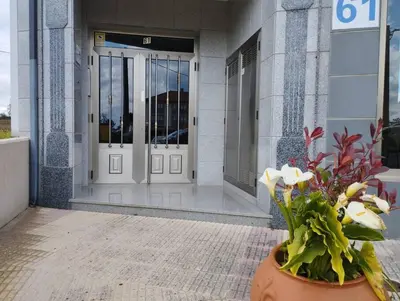 a vase of flowers in front of a building at Fogar do Vento-Ordes, cerca de Camino Inglés Bruma in Ordes