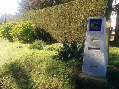 a sign sitting in the grass next to a fence at Fogar do Vento-Ordes, cerca de Camino Inglés Bruma in Ordes