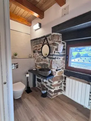a bathroom with a stone wall and a toilet at 27A01 Casa Uría Cam Santiago by R2R Consulting in Berducedo