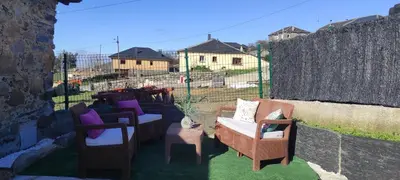 a patio with chairs and a cat sitting on it at 27A01 Casa Uría Cam Santiago by R2R Consulting in Berducedo