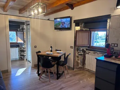 a dining room with a table and a tv on the wall at 27A01 Casa Uría Cam Santiago by R2R Consulting in Berducedo