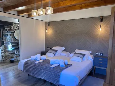a bedroom with a large bed with blue pillows at 27A01 Casa Uría Cam Santiago by R2R Consulting in Berducedo