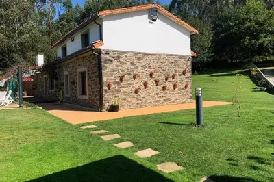 a stone building with a grassy yard next to it at A chousa da folgueira in Ordes
