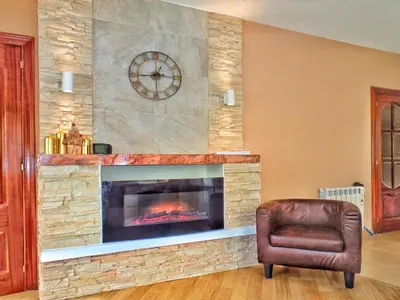 a living room with a fireplace with a chair and a clock at Casa en Cortiñan in Bergondo