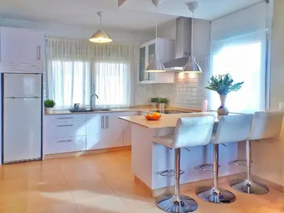 a kitchen with white cabinets and a island with bar stools at Casa en Cortiñan in Bergondo