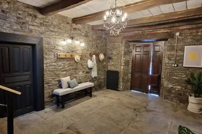 a room with a stone wall with a bench and a chandelier at La Escondida VuT-LE-952 in Caboalles de Abajo