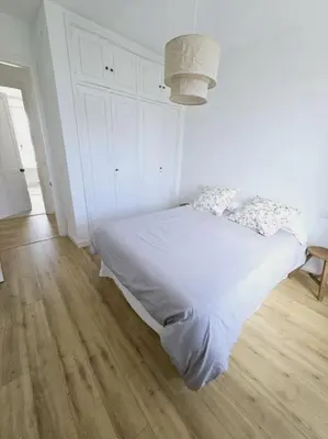 a white bedroom with a white bed and a wooden floor at Apartamento en plaza de Ribadeo in Ribadeo