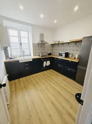 a kitchen with black cabinets and a wooden floor at Apartamento en plaza de Ribadeo in Ribadeo