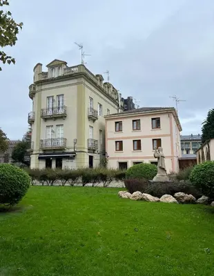 a large building with a statue in front of a yard at Apartamento en plaza de Ribadeo in Ribadeo