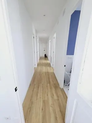 a long hallway with white walls and a wooden floor at Apartamento en plaza de Ribadeo in Ribadeo