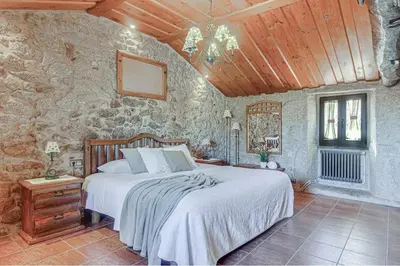 a bedroom with a bed and a stone wall at Villamia in Coirós