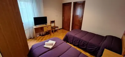 a living room with a purple couch and a television at Pensión Río Cenza in Villarino de Conso